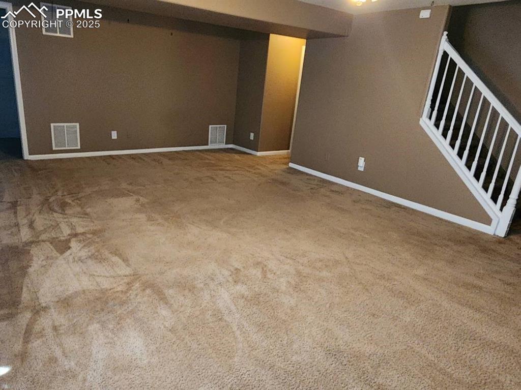 Finished below grade area featuring stairway and light colored carpet