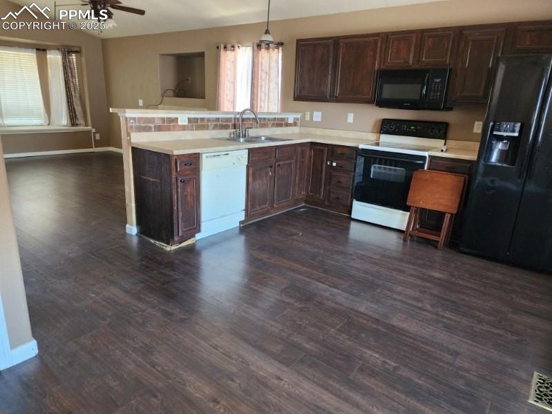 Kitchen featuring dark brown cabinets, black appliances, light countertops, a peninsula, and dark wood-type flooring