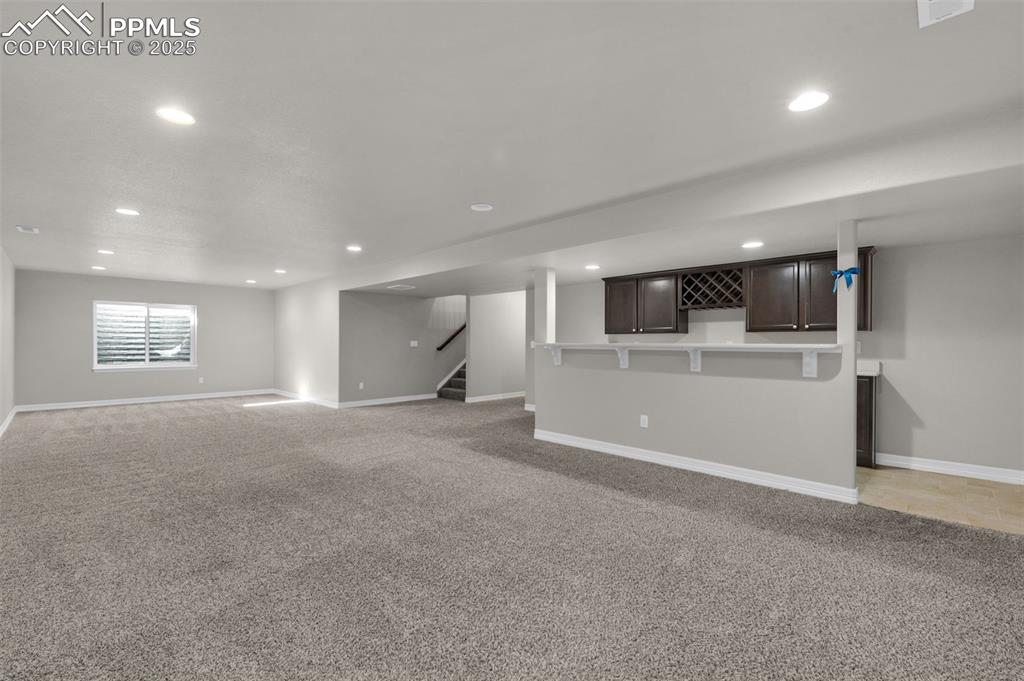 Unfurnished living room with light colored carpet, recessed lighting, and stairway