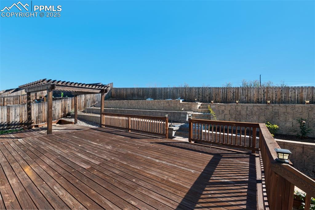 Wooden deck featuring a fenced backyard and a pergola