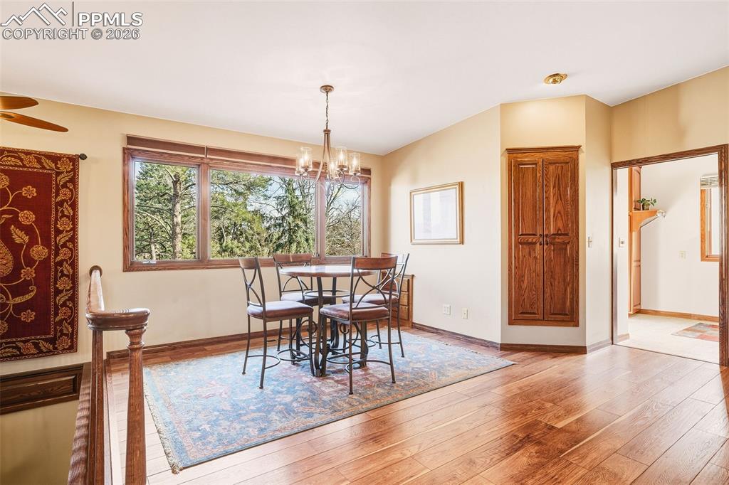 Light-filled dining space framed by expansive windows with peaceful treetop views. Hardwood flooring and updated lighting create an inviting setting for everyday meals or gatherings.