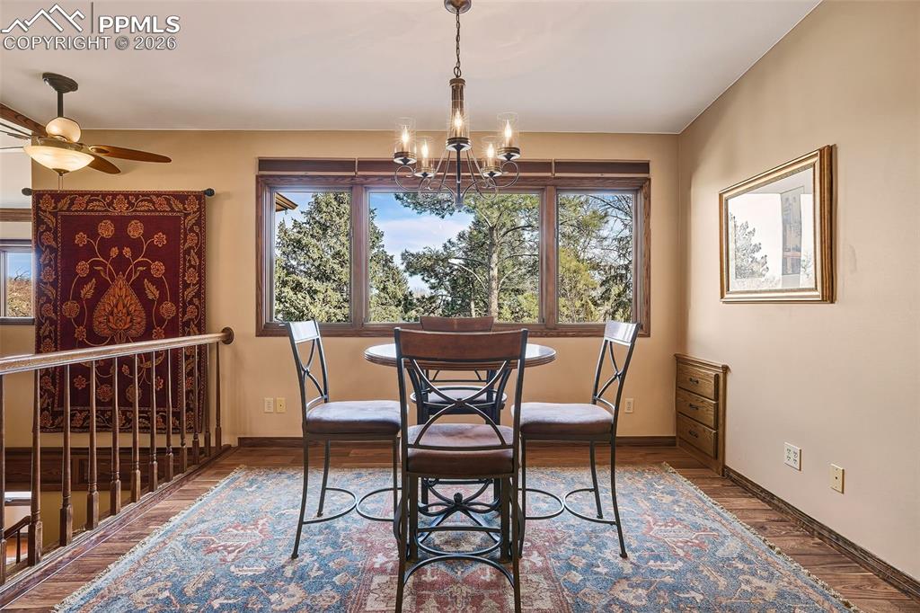 Inviting dining space with wood flooring, statement chandelier, and expansive windows framing peaceful treetop views. Positioned perfectly for everyday meals or casual gatherings.