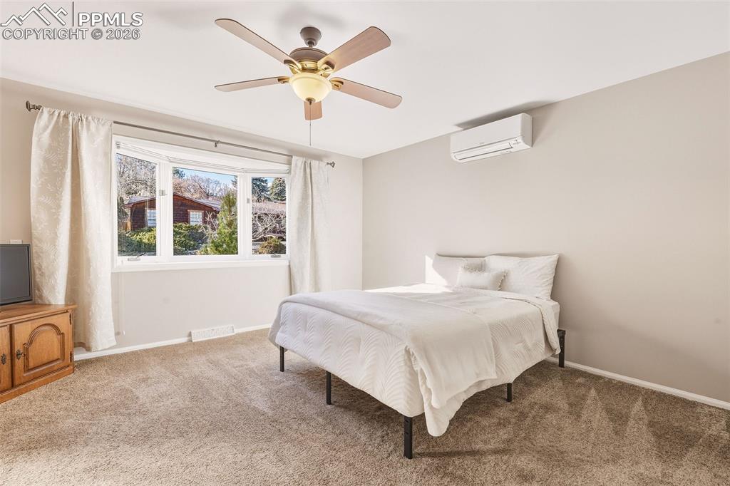 Spacious main-level retreat with carpet, large picture window, ceiling fan, and wall-mounted mini split for individualized climate comfort.