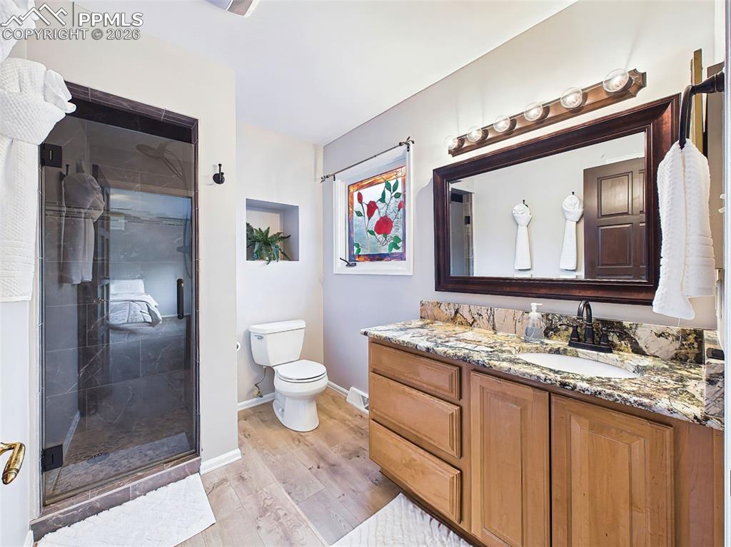Updated three-quarter bath featuring a refinished walk-in shower, granite countertop, and warm wood cabinetry. Modern fixtures and upgraded flooring add both style and functionality.