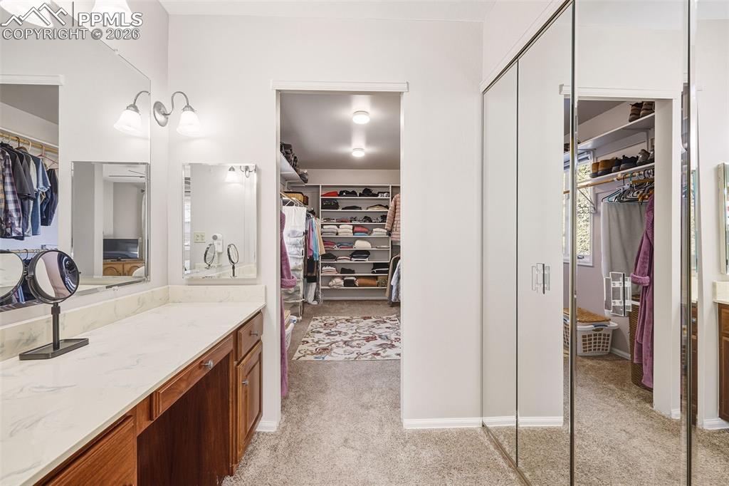Dedicated vanity space with countertop storage and dual mirrors, seamlessly connected to the expansive walk-in closet for added functionality.