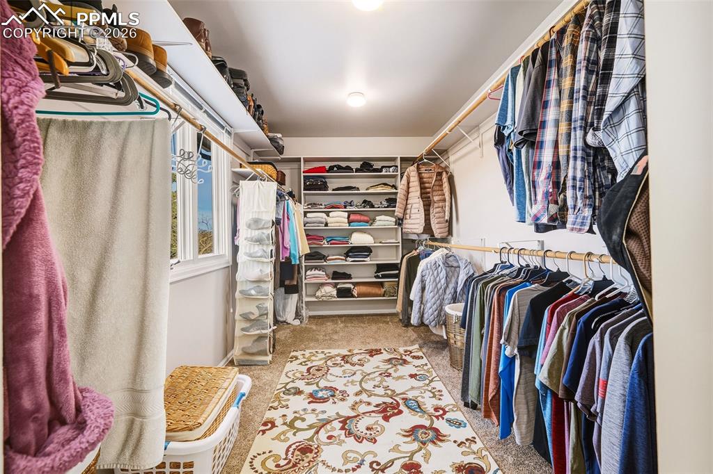 Spacious walk-in closet with custom shelving, dual hanging rods, and natural light, offering generous storage and organization.