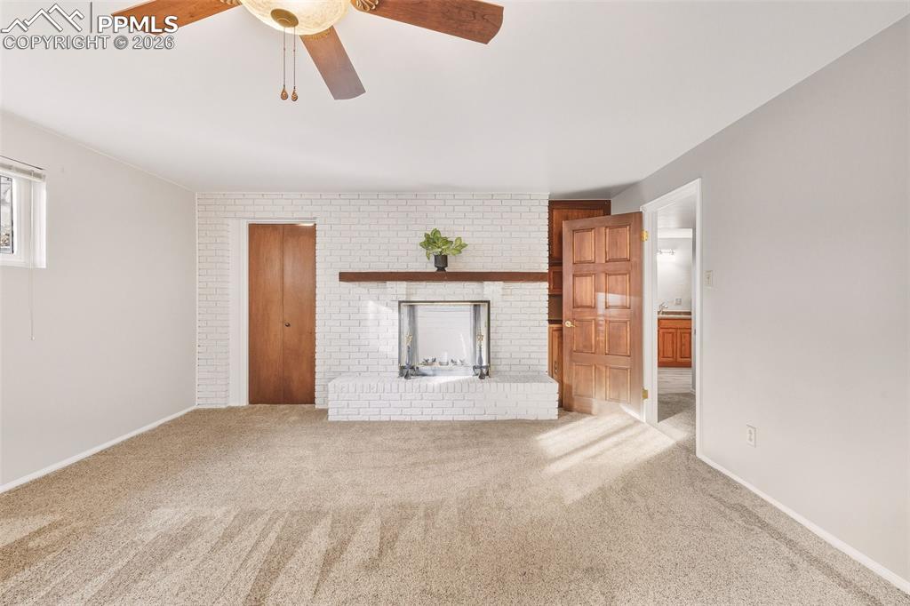 Expansive bedroom #3 showcasing a white brick fireplace with wood mantel, generous floor space.