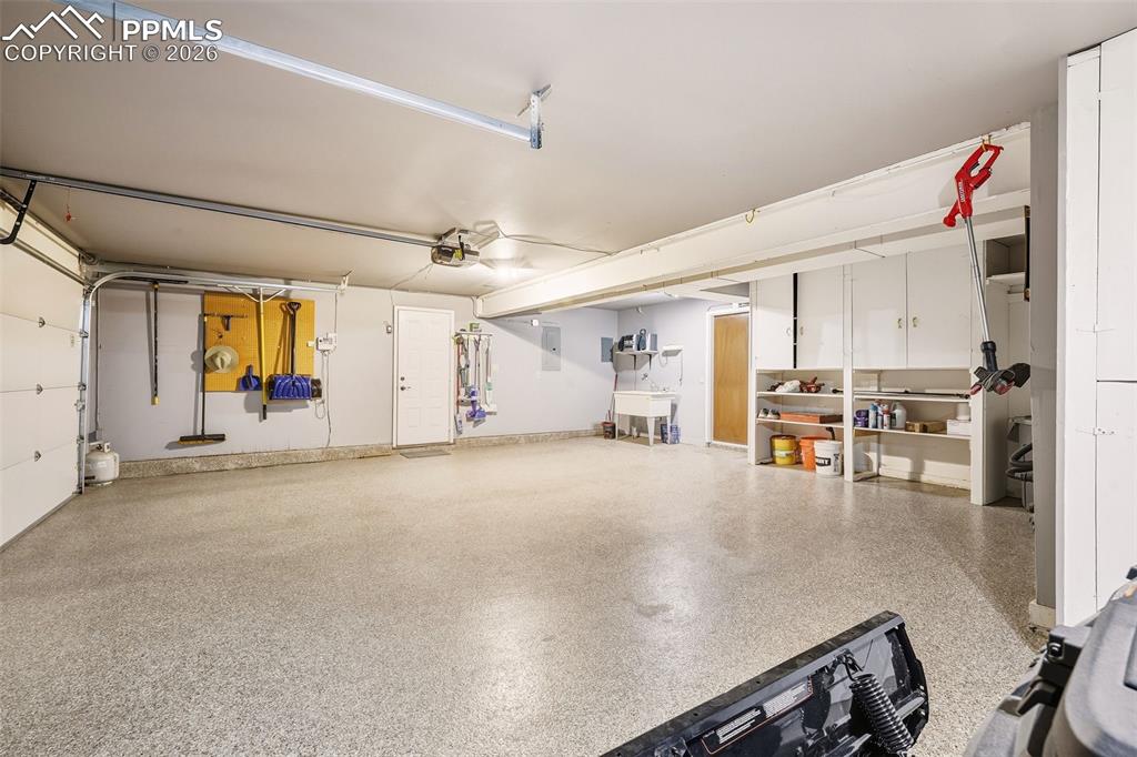 Oversized garage with epoxy-coated flooring, built-in shelving, utility sink, and workshop space—designed for both storage and functionality.