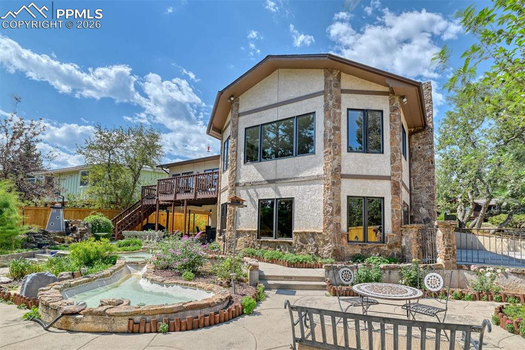 Beautifully landscaped yard with winding walkways, water features, and mature trees, all enclosed by upgraded fencing for added privacy.