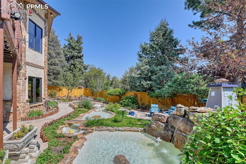 Custom-designed backyard sanctuary featuring multiple concrete ponds, flowing water elements, and thoughtfully designed landscaping for a peaceful outdoor experience.