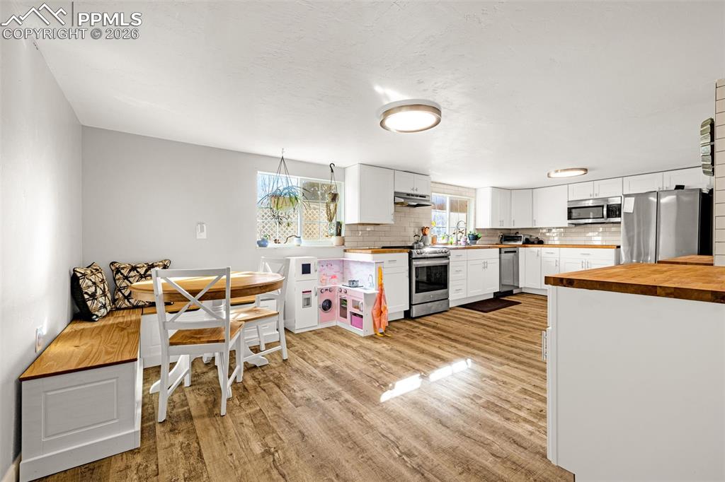 Kitchen featuring decorative backsplash, butcher block countertops, stainless steel appliances, and white cabinetry