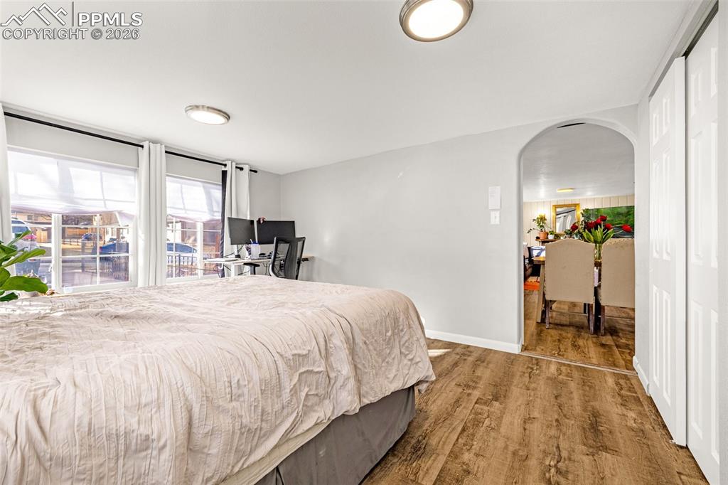 Bedroom featuring arched walkways, dark wood finished floors, and a closet