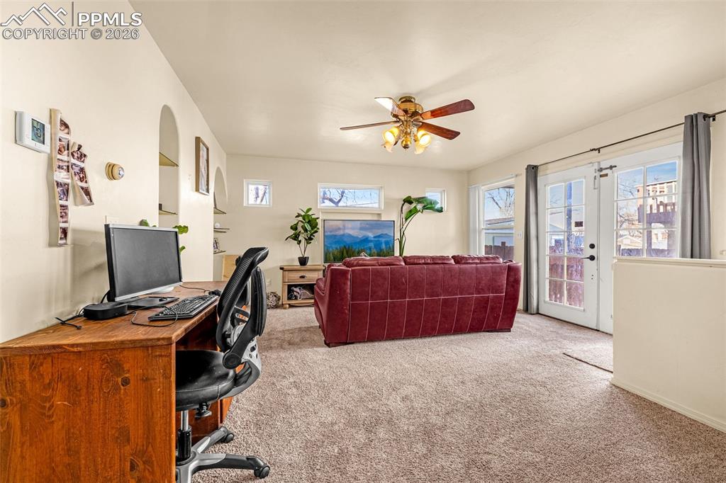 Home office featuring light colored carpet, ceiling fan, and french doors