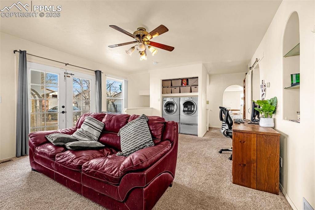 Living area with built in shelves, carpet flooring, ceiling fan, and french doors