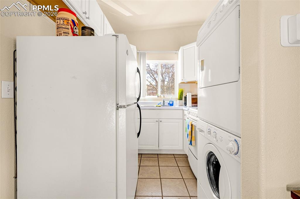 ADU Laundry area featuring light tile patterned floors and stacked washer and dryer