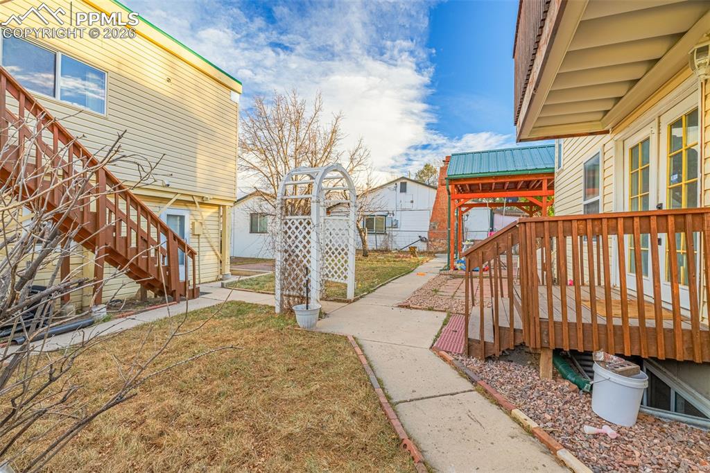 View of grassy yard with stairway and a deck