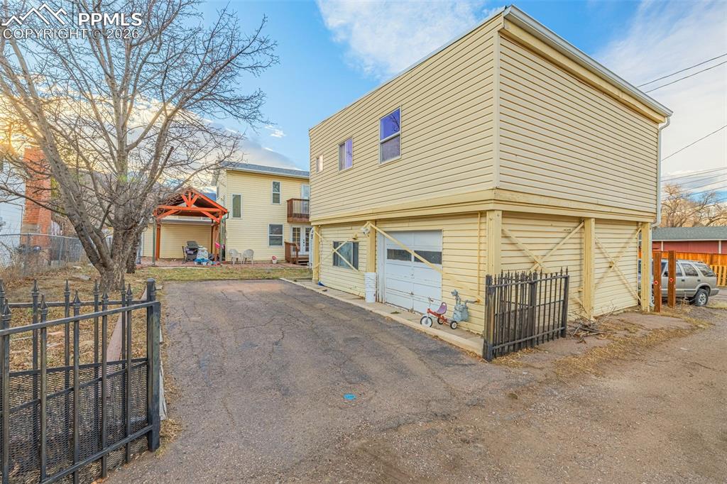 View of ADU property exterior featuring a patio, an attached garage, and asphalt driveway