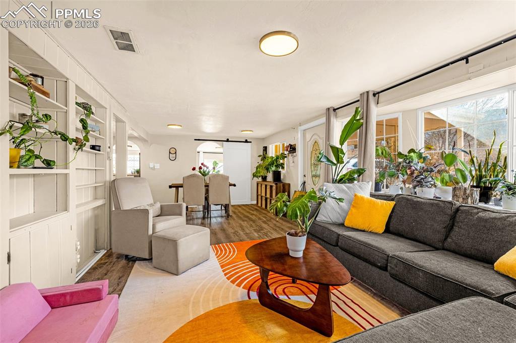 Living area with wood finished floors, a barn door, and built in shelves