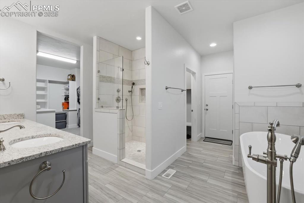 The primary bathroom features dual vanities, a separate tub and shower and beautiful tile work. 