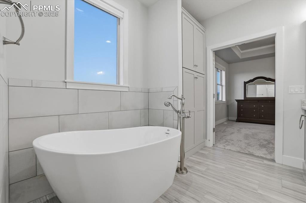 The primary bathroom has an elegant soaking tub with floor-mounted fixtures. 