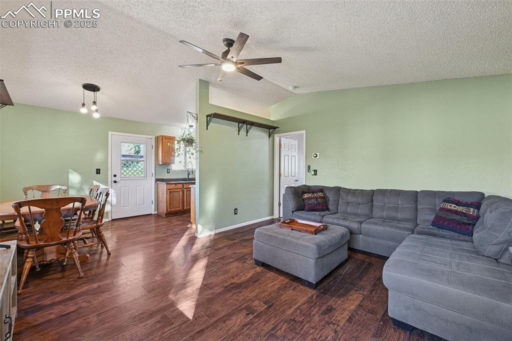 Living area with dark wood-style floors, ceiling fan, and a textured ceiling