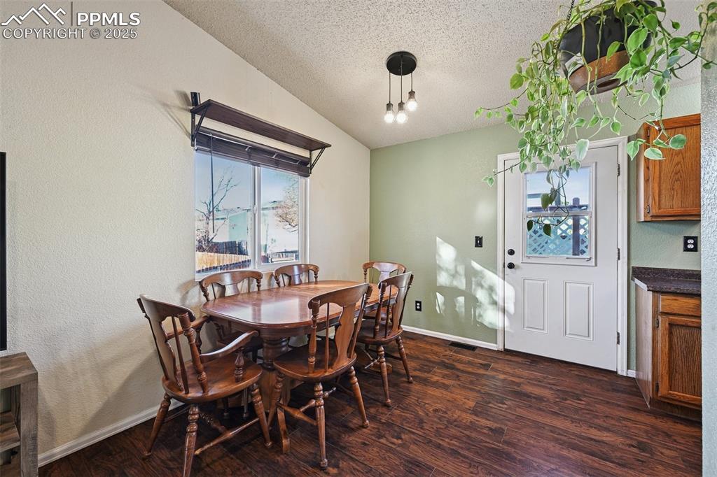 Dining space, dark wood-type flooring, a textured ceiling, and a textured wall