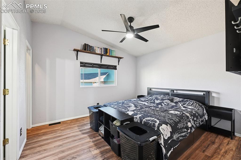 Bedroom featuring, wood finished floors, a textured ceiling, and ceiling fan