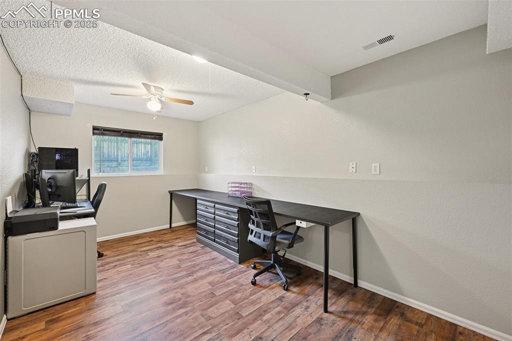 Office featuring light wood-style flooring, a textured ceiling, a textured wall, and a ceiling fan
