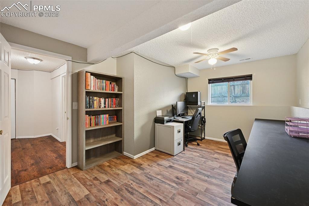 Office featuring a textured ceiling, light wood-style flooring, and a ceiling fan