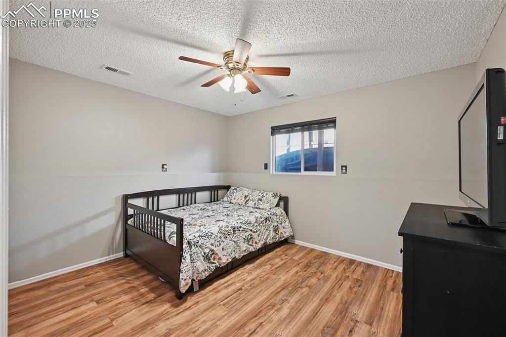 Bedroom featuring light wood-type flooring, a ceiling fan, and a textured ceiling