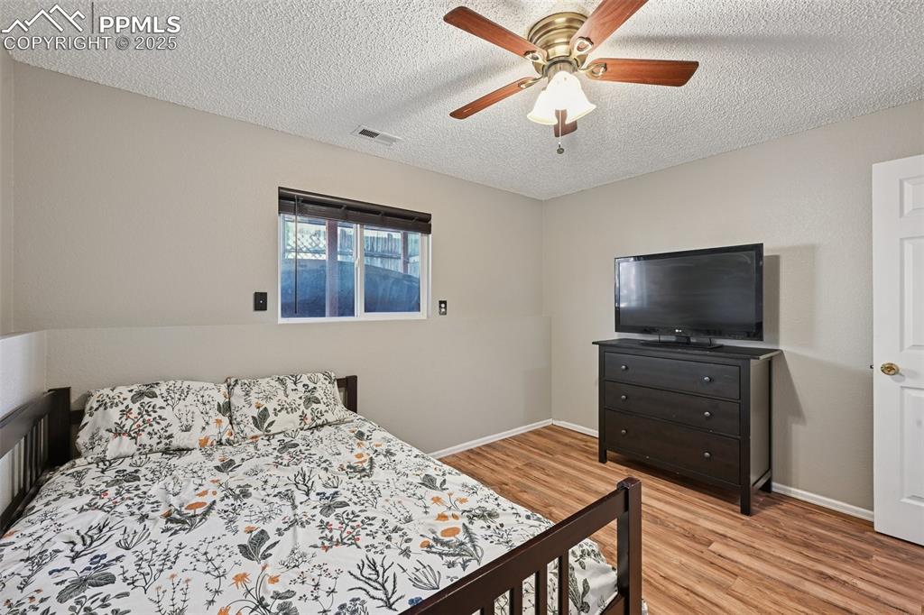 Bedroom featuring light wood finished floors, a textured ceiling, and a ceiling fan
