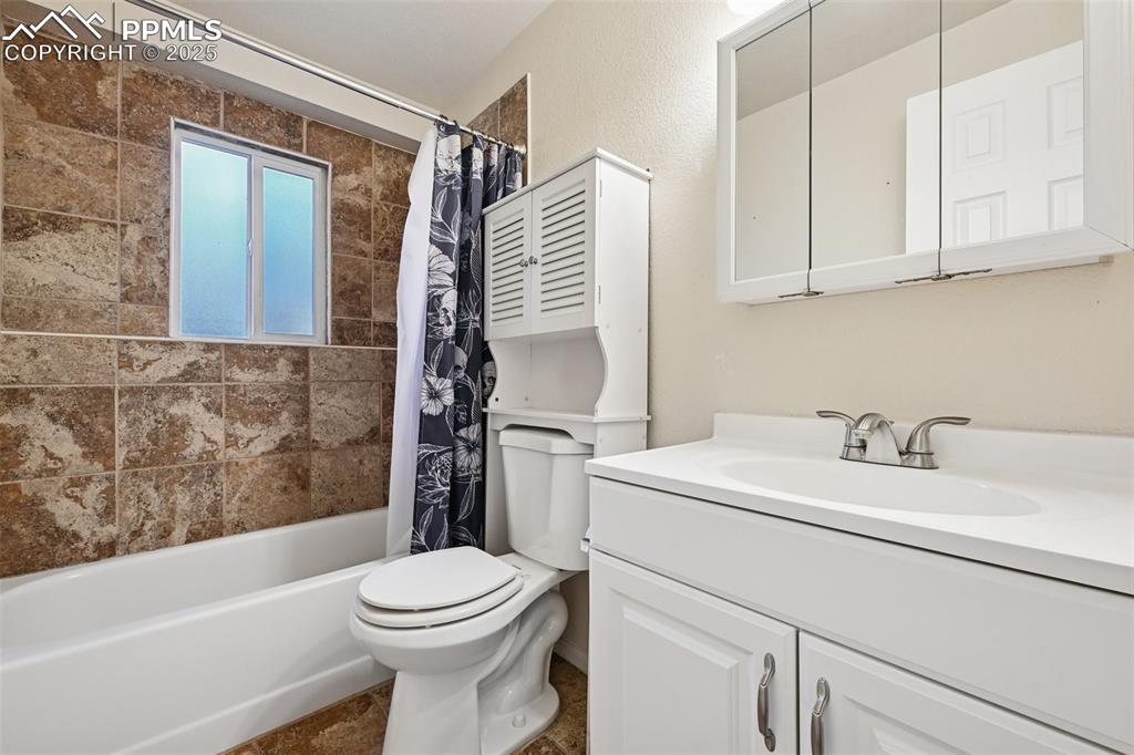 Bathroom featuring shower / bath combination with curtain and vanity
