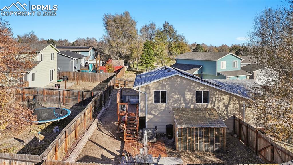 Back of house featuring a fenced backyard, a residential view, a trampoline, and a patio