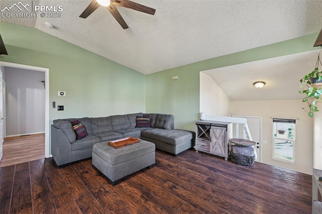 Living area featuring a textured ceiling, dark wood-style floors, and a ceiling fan
