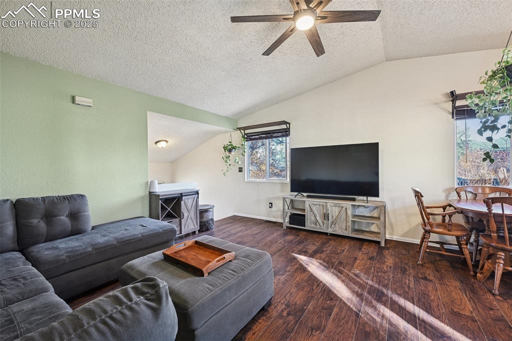 Living room with, a textured ceiling, dark wood finished floors, and a ceiling fan