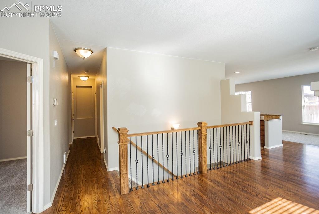 Corridor featuring an upstairs landing and dark wood-style flooring