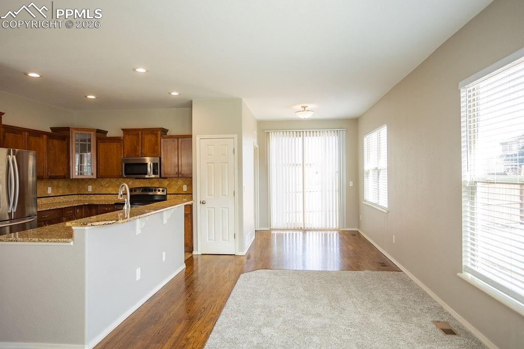 Kitchen with glass fronted cabinets, stainless steel appliances, dark wood finished floors, decorative backsplash, and wood finish cabinets