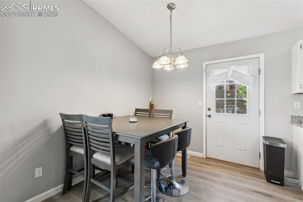 Dining room featuring a chandelier, lofted ceiling, and light wood-type flooring