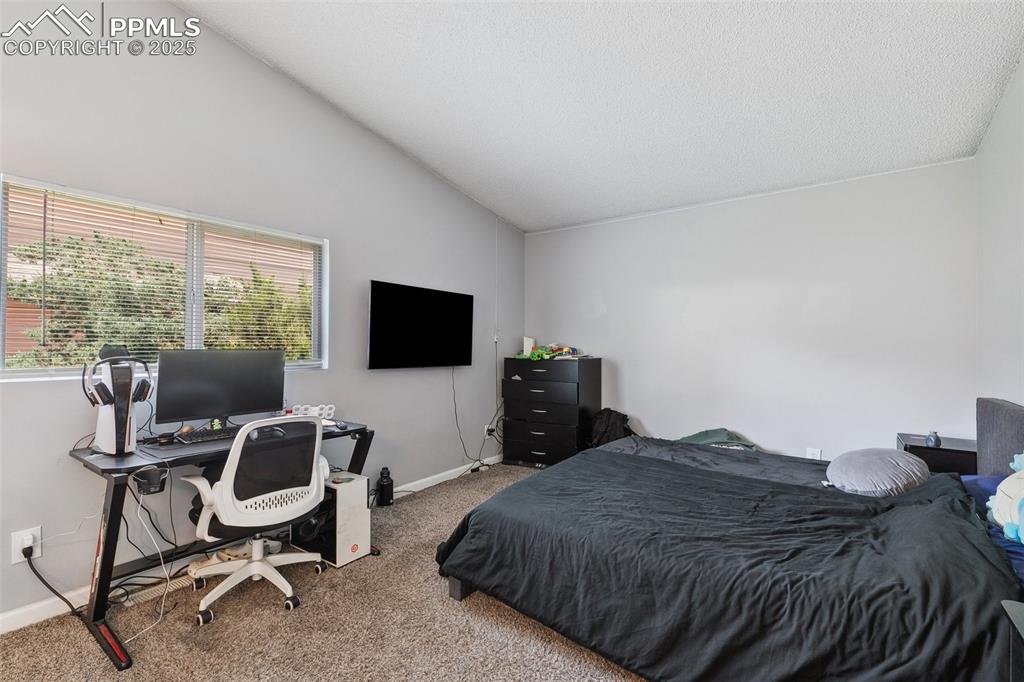 Carpeted bedroom with lofted ceiling and a desk