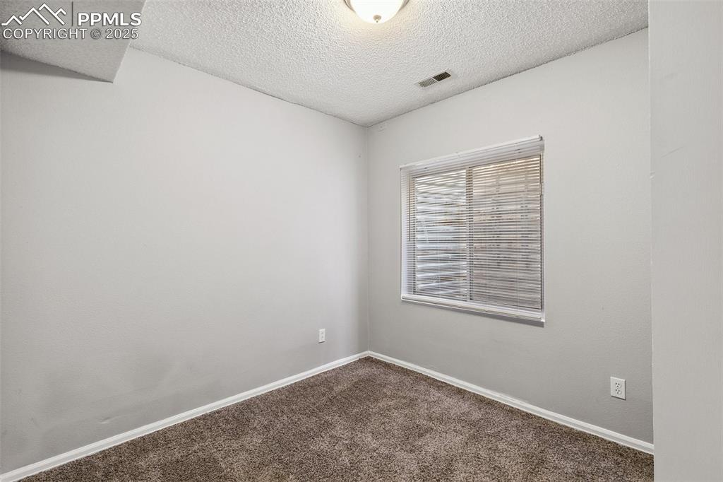 Empty room with dark carpet and a textured ceiling