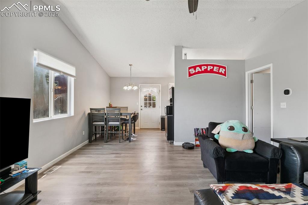 Living room featuring wood finished floors, a chandelier, a ceiling fan, and a textured ceiling