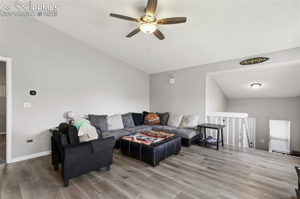 Living room featuring lofted ceiling, ceiling fan, and wood finished floors