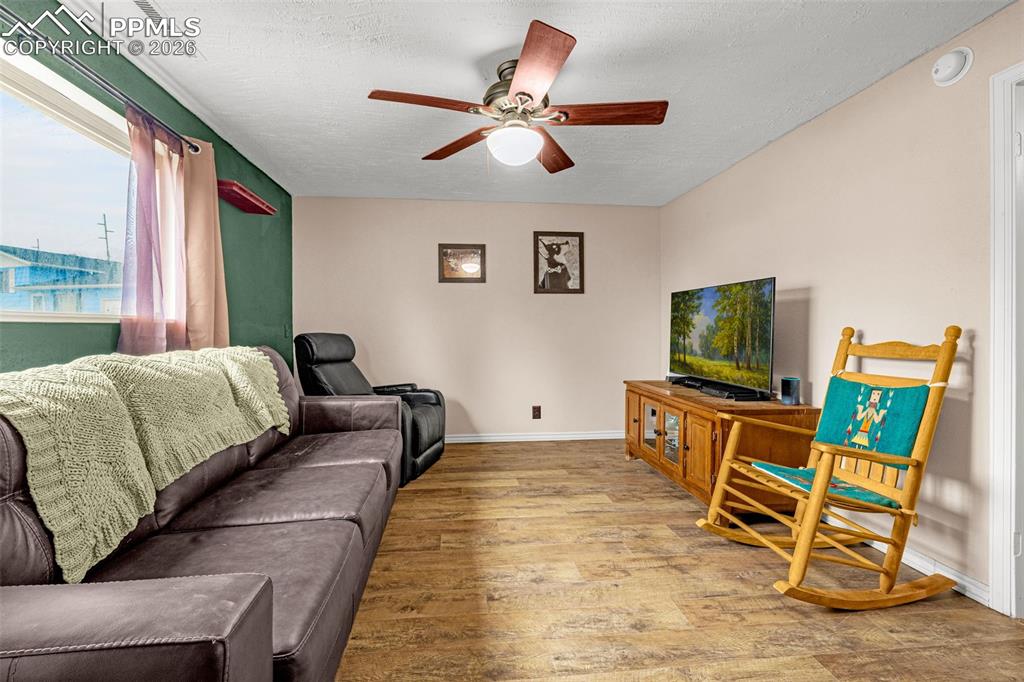 Living area with hardwood / wood-style flooring, a ceiling fan, and a textured ceiling