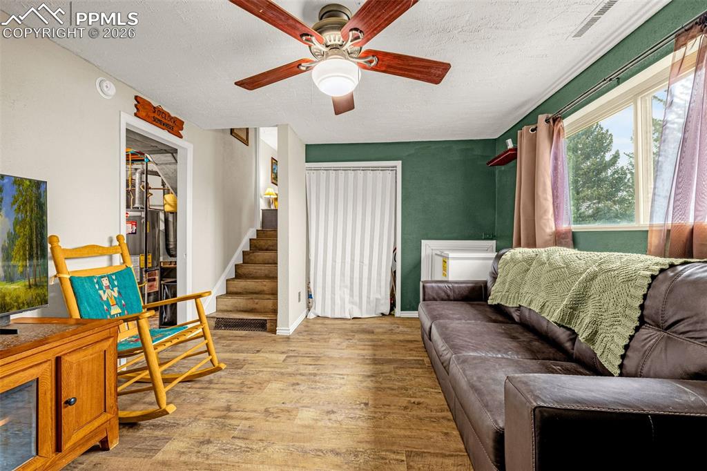 Living area with a textured ceiling, light wood-style flooring, and ceiling fan