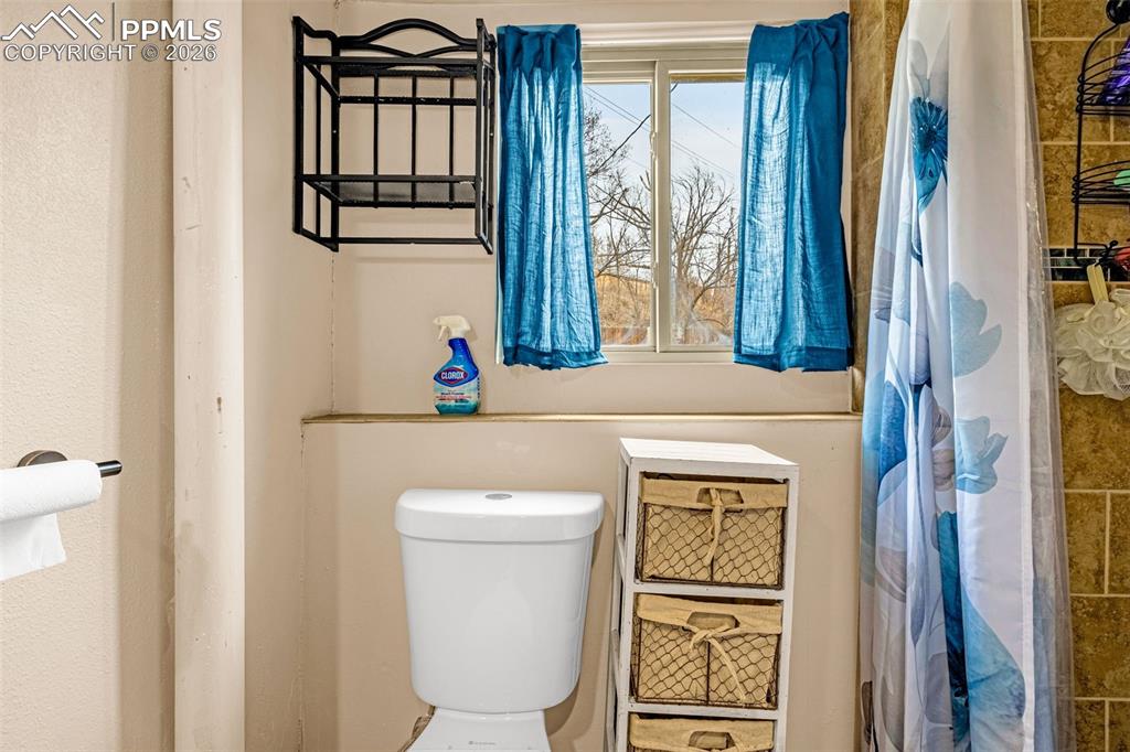 Full bath with toilet and a shower with shower curtain