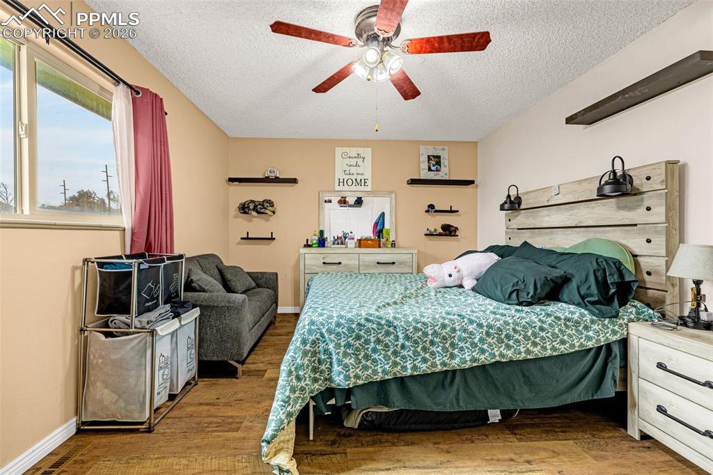Bedroom featuring wood finished floors, a ceiling fan, and a textured ceiling