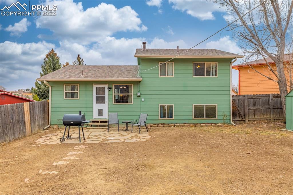 Rear view of property featuring a patio area, a fenced backyard, and a shingled roof