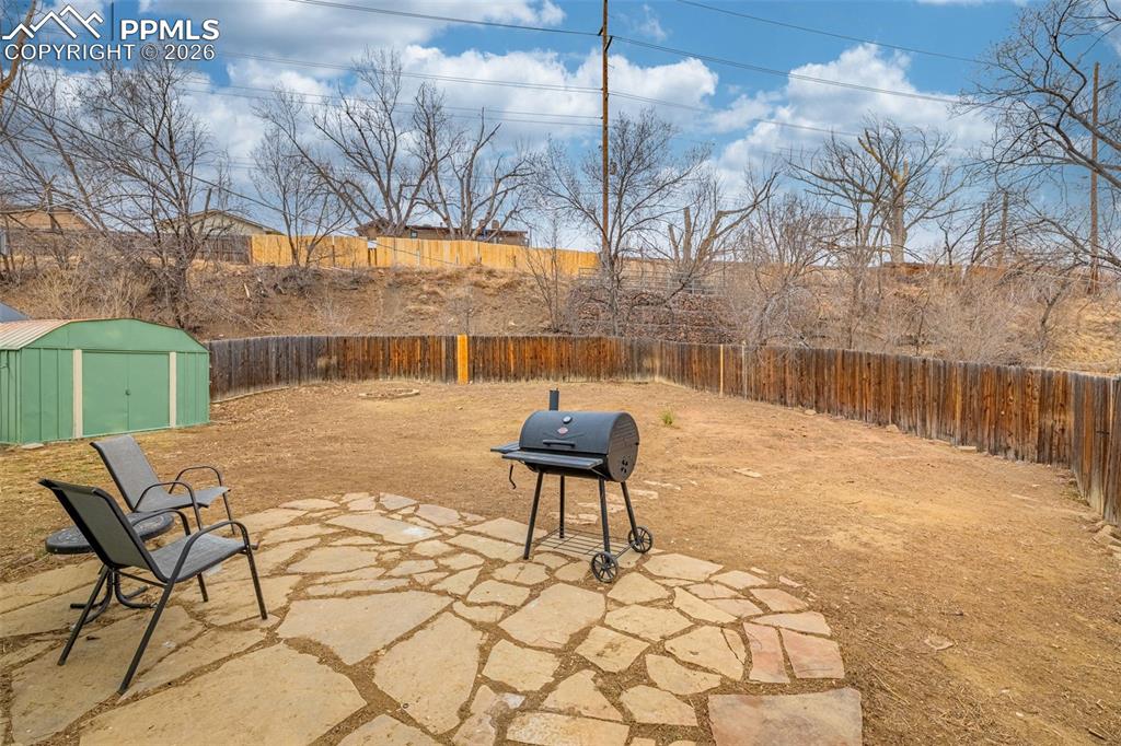 Fenced backyard with a patio, area for grilling, and a storage shed
