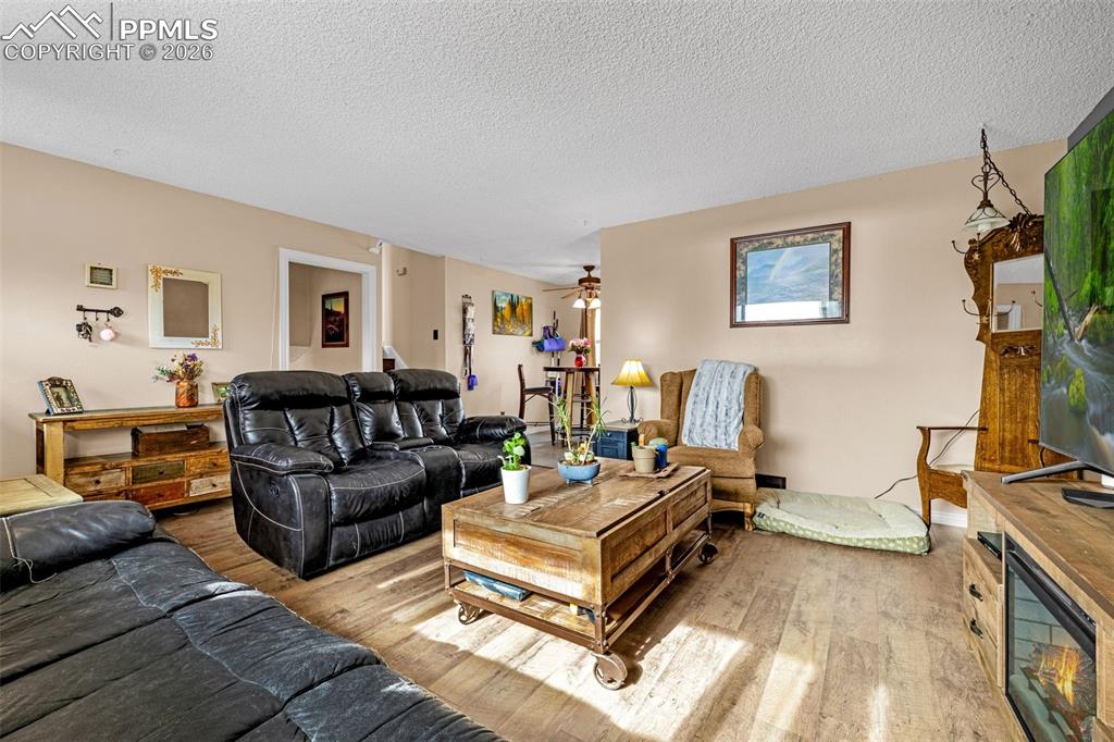 Living room featuring ceiling fan, wood finished floors, and a textured ceiling