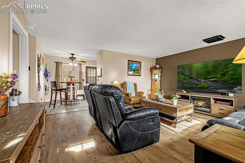 Living area with hardwood / wood-style flooring, a textured ceiling, and a ceiling fan